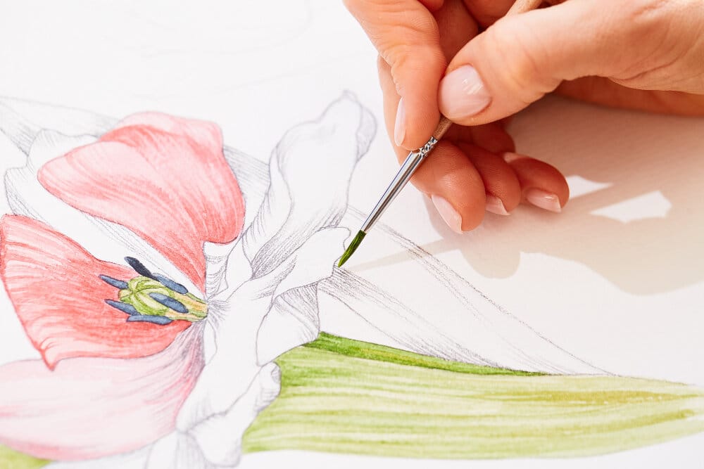 With a paintbrush painting the flower